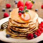 american pancake stack with syrup and fruit